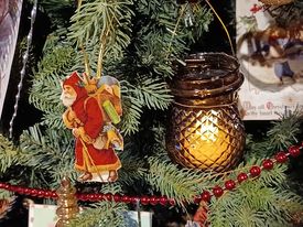 Close up of Christmas tree with fairy lamp and paper Santa ornament