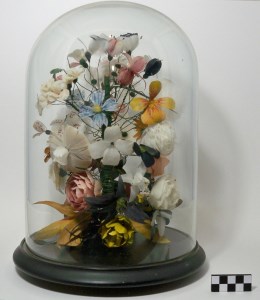Glass terrarium with floral arrangement made of feathers