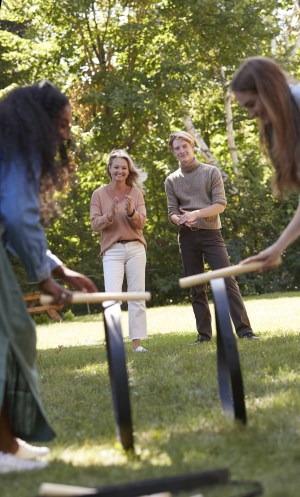 two women playing barrel hoops while two other people observe