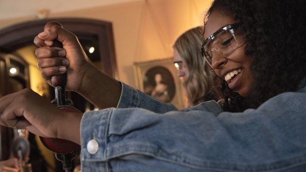 Woman wearing safety goggles holding hand drill