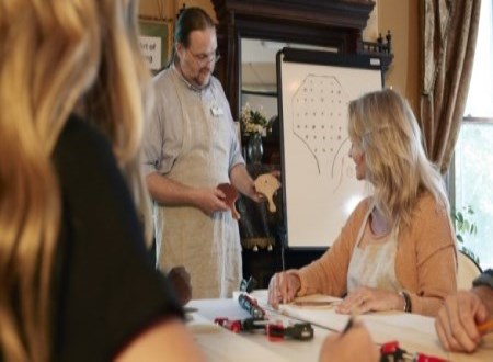 a man with long hair and glasses demonstrating how to make a reproduction peg solitaire game