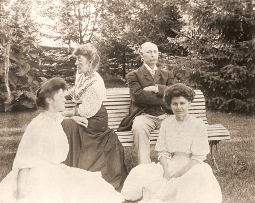 Photograph of Harriet and John Phillips sitting on a bench with Jesise and a school friend sitting on the ground