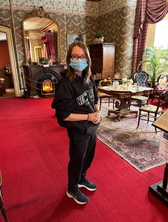 Photo of Hannah (teenage girl with shoulder length hair and glasses) standing in the Master Bedroom at Glanmore