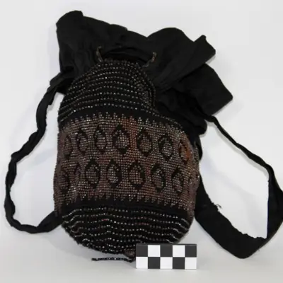 A black Victorian reticule, small drawstring bag, with beaded pattern.