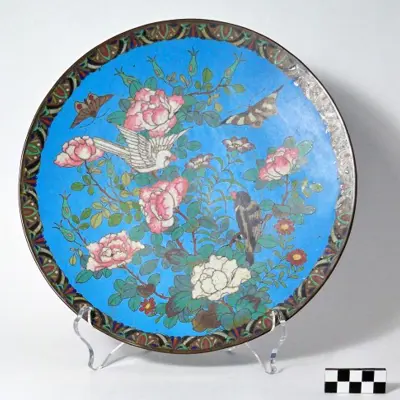 Blue cloisonné plate with birds, butterflies, and primarily pink flowers.