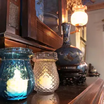 two fairy lamps, small glass votive candle holders, sit on a fireplace mantle